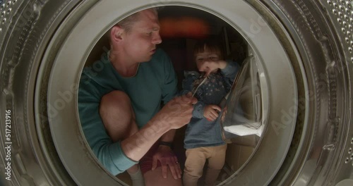 Dad sings a song to a wrench with a board in a washing machine drum. He emits a microphone, the girl sings. Motivation with the support of a young father, repair.
