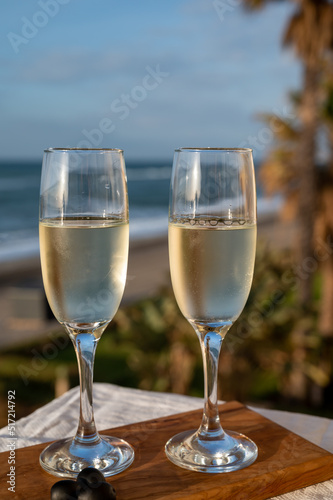 Glasses of Spanish cava sparkling wine and view on blue sea and sandy beach, Costa del Sol vacation destination, Andalusia, Spain