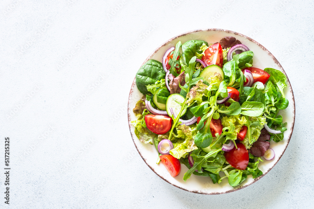 Salad in white plate. Fresh green leaves and vegetables salad. Healthy vegan food, diet food. Top view, copy space. Salad in white plate. Fresh green leaves and vegetables salad. Healthy vegan food, diet food. Top view, copy space.