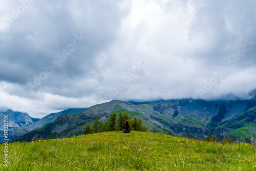 A wide angle shot of a young female hiker on a break during a hike on a cloudy summer day in the French Alps (Valberg, Alpes-Maritimes, France) © k.dei