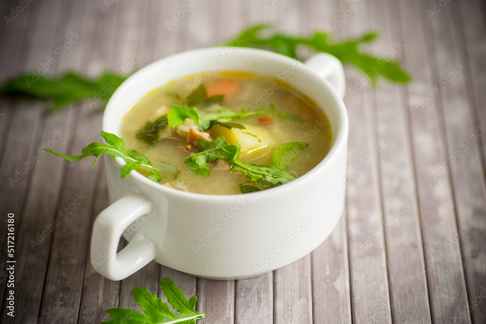 summer light soup with oatmeal and arugula in a plate summer light soup with oatmeal and arugula in a plate