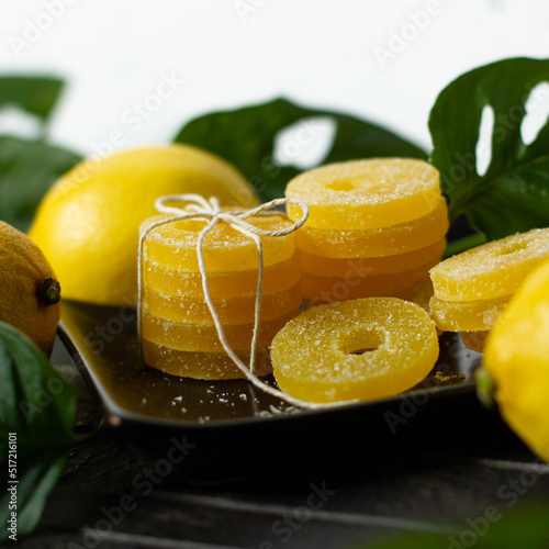Lemon, orange and grapefruit slices in sugar isolated on a wooden background, close-up. Marmalade sweets. Sweets with citrus flavor. Candies