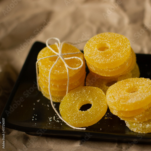 Lemon, orange and grapefruit slices in sugar isolated on a wooden background, close-up. Marmalade sweets. Sweets with citrus flavor. Candies