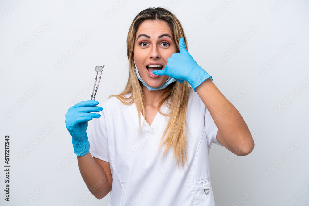 Dentist woman holding tools isolated on white background making phone gesture. Call me back sign Dentist woman holding tools isolated on white background making phone gesture. Call me back sign