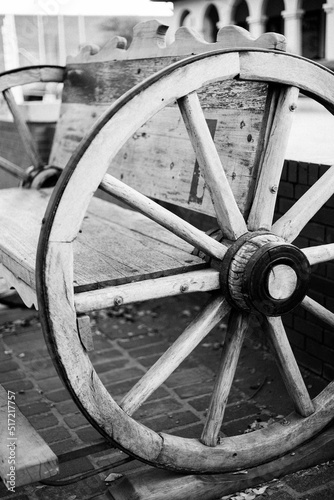 Grayscale shot of a wooden wagon wheel bench located in the Fort Worth, Texas Stockyards photo