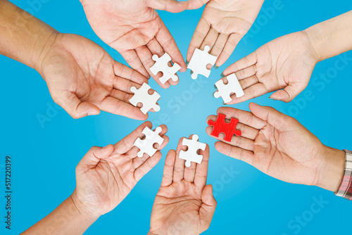 Close up Businesspeople hand holding jigsaw puzzle in a circle on the table on blue background, success and strategy concept.