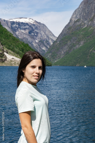 Young tourist woman in the foreground and behind her the fjord with the high mountains in Gudvangen - Norway