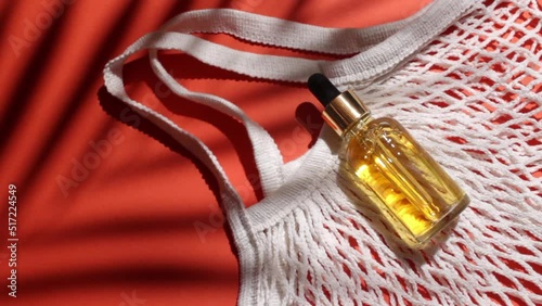Cosmetic bottle with oil and cloth shopping bag. Red background with daylight and palm shadow. Sun protection lotion, sunscreen. Summer skin care concept with spf.