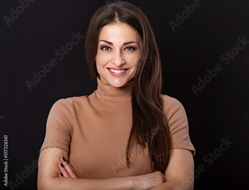 Beautiful young business toothy smiling woman thinking and looking happy on dark black background with empty copy space. Portrait