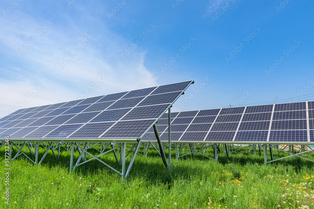 Solar panels on the green fields with blue sky background