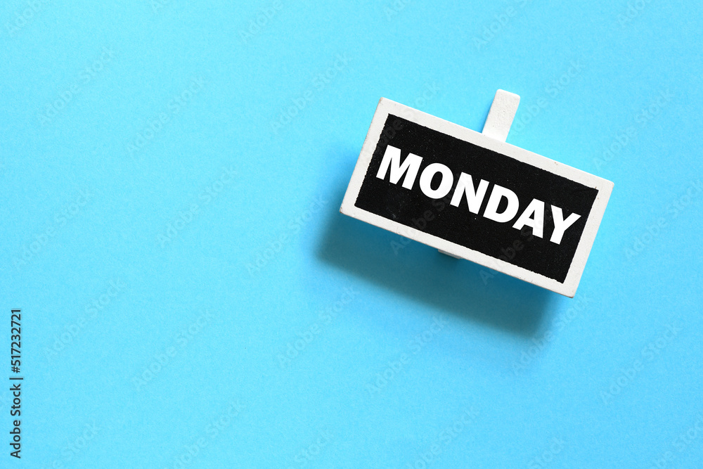 The word MONDAY on a small chalk board over a blue background. The word MONDAY on a small chalk board over a blue background.