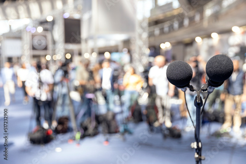 Microphone in focus at media event, press or news conference, blurred video camera operators in the background