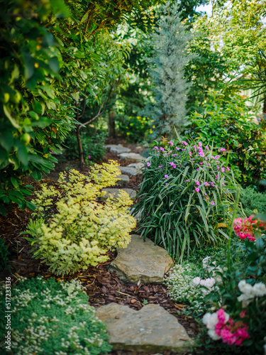 Landscape design with flower beds and path, natural landscaping in home garden. Beautiful view of nice landscaped garden