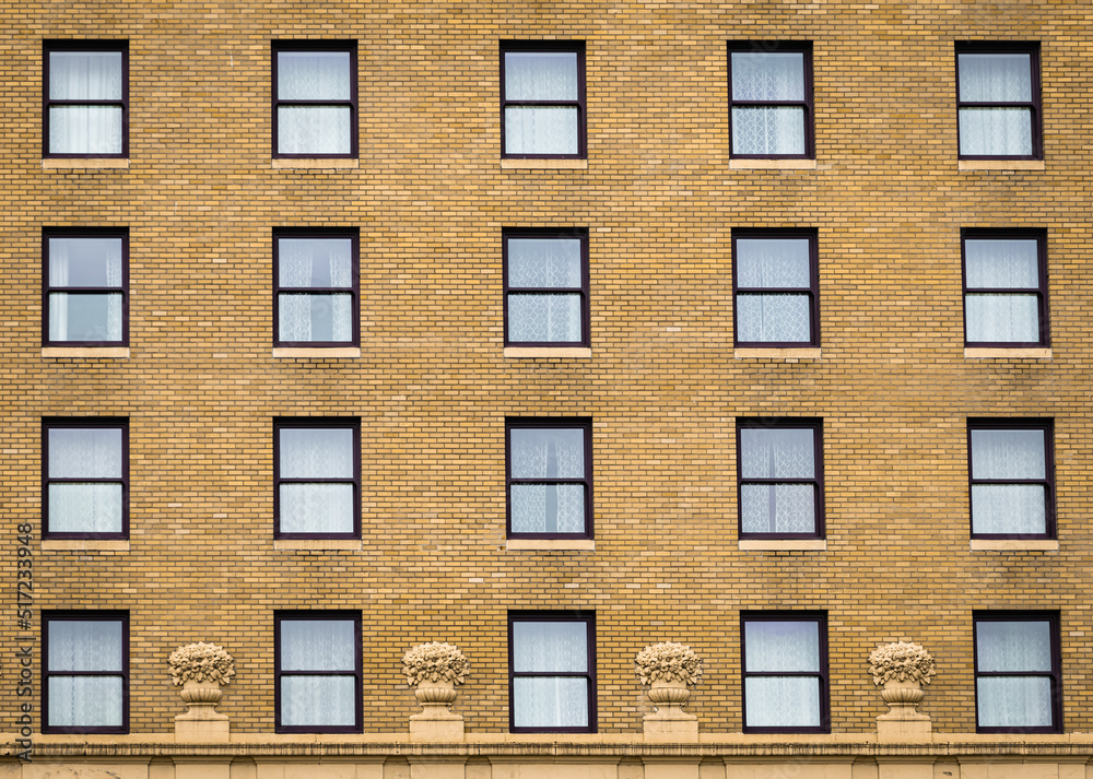 Many windows in row on facade of urban apartment building. Brick building.