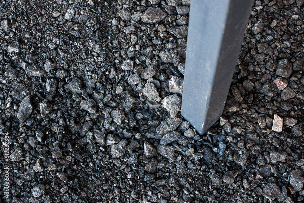 Surface grunge rough of asphalt and an iron post dug into the ground, texture background, tarmac grey grainy road, top view Surface grunge rough of asphalt and an iron post dug into the ground, texture background, tarmac grey grainy road, top view