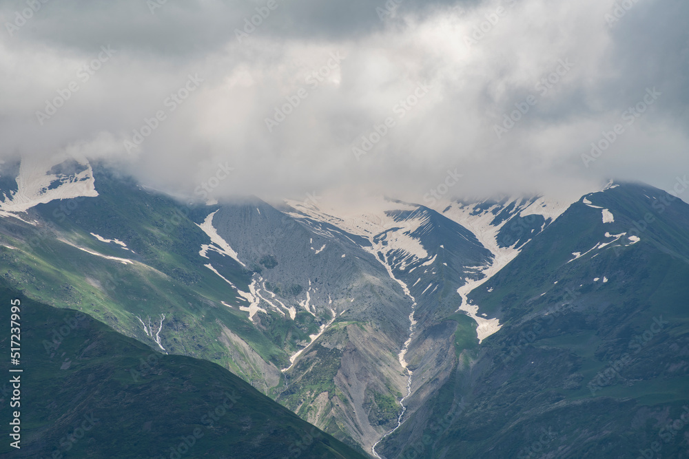 Fototapeta premium Clouds over the snow covered mountains. High mountains peak, winter landscape.
