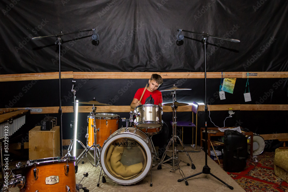 Fototapeta premium a young drummer plays drums, cymbals with sticks, sitting on a special chair