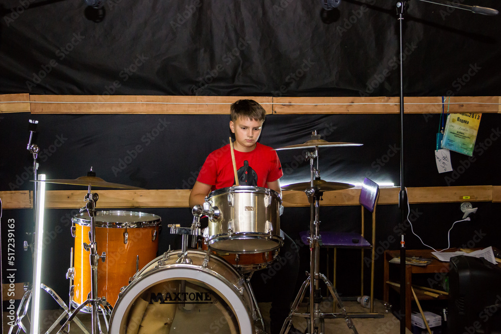 Fototapeta premium a young drummer plays drums, cymbals with sticks, sitting on a special chair