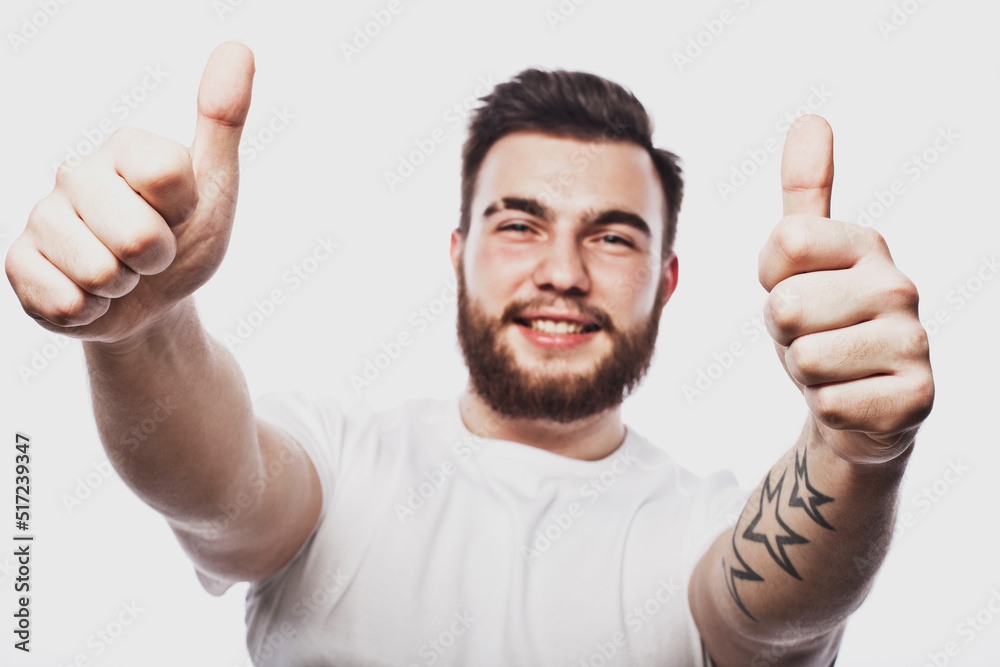 Portrait of a cheerful young bearded man showing okay gesture isolated on the white background Portrait of a cheerful young bearded man showing okay gesture isolated on the white background
