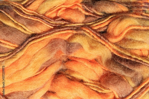 Close-up of colourful merino wool orange striped background. Abstract handmade craft knitting yarn textured pattern flatlay. Holiday autumn fall concept. Idea for felting, needlework, hobby. Mock up