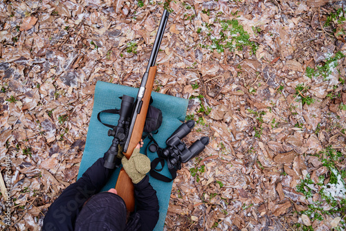 Young man aiming at target with the hunting rifle. photo