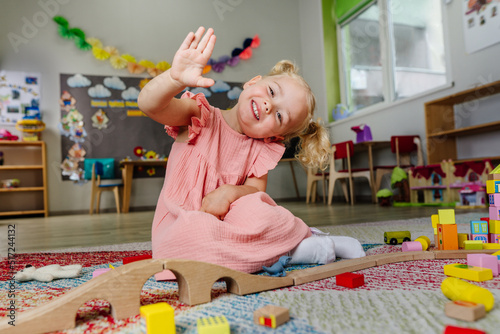 Toddler girl playing with wooden train in kindergarten photo