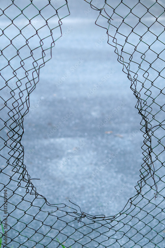 Hole in the fence. Mesh wire boundary. Steel mesh barrier fence. Chain link fence with Hole. Hole in the fence. Mesh wire boundary. Steel mesh barrier fence. Chain link fence with Hole.