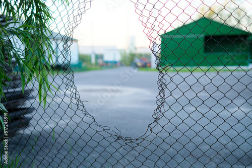 Hole in the fence. Mesh wire boundary. Steel mesh barrier fence. Chain link fence with Hole.