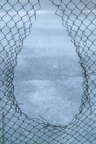 Hole in the fence. Mesh wire boundary. Steel mesh barrier fence. Chain link fence with Hole.
