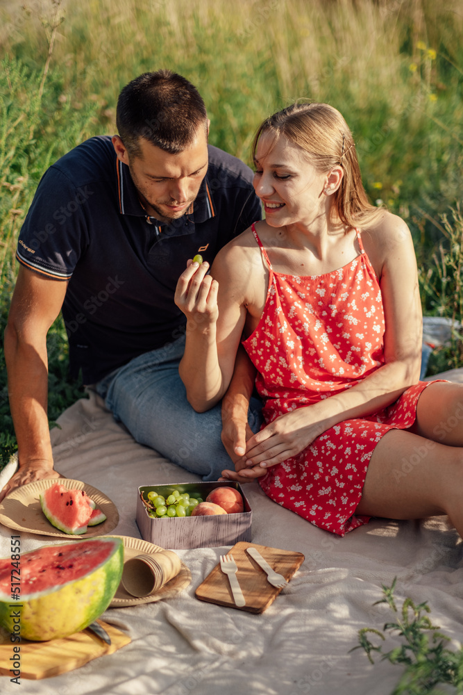 Happy flirting loving couple kissing and having date outdoors. Young couple on summer picnic with watermelon. Happy flirting loving couple kissing and having date outdoors. Young couple on summer picnic with watermelon.