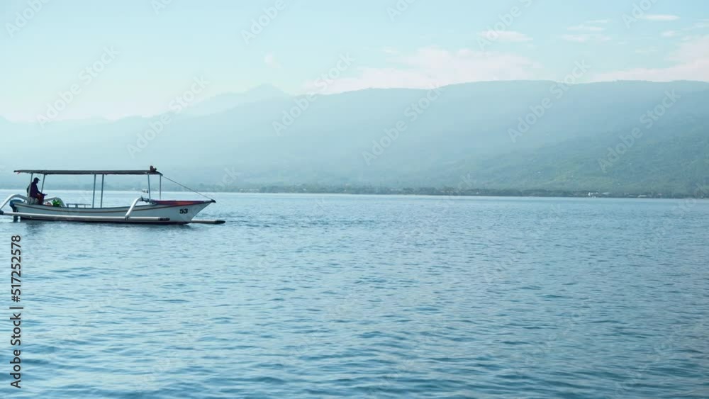 People on a boat sail behind the Stenellalongirostris family of dolphins that jump out of the water in the open, clear sea on the island of Bali People on a boat sail behind the Stenellalongirostris family of dolphins that jump out of the water in the open, clear sea on the island of Bali