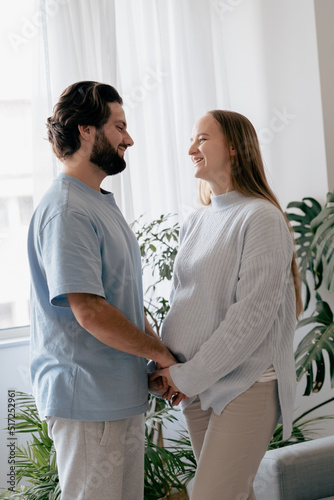 Happy young future parents waiting for childbirth, showing love and affection to unborn child. Loving husband looking with tenderness at his pregnant wife. Parenthood concept. Mothers Day