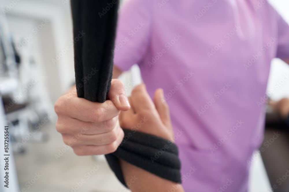 Physiotherapist and patient hands with physical therapy exercise rope