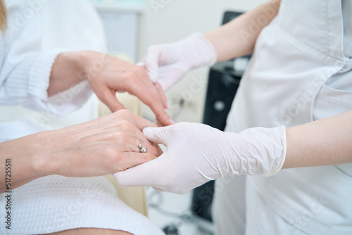 Doctor in gloves examines the hands of the patient after the procedure