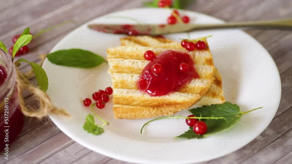 fried bread croutons for breakfast with redcurrant jam in a plate with berries on a wooden table. fried bread croutons for breakfast with redcurrant jam in a plate with berries on a wooden table.