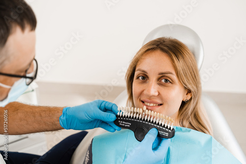 Tooth whitening. Dentist working with teeth color shades guide. Dentistry. Doctor checking teeth color matching samples in dental clinic.
