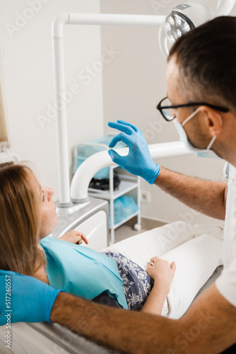 Dentist showing dental veneer teeth implant to woman patient in dental clinic. Dentistry. Consultation with dentist about tooth implantation and whitening.