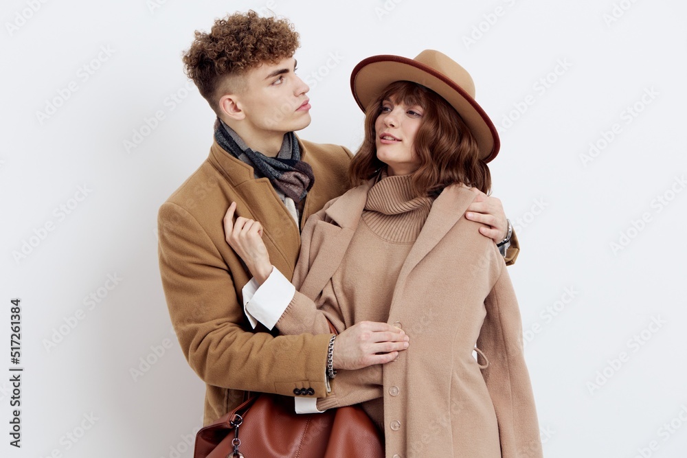 a sweet, joyful, pleasant stylish couple stands on a white background in autumn coats and gently hug each other, a man holds a woman by the coat looking at her a sweet, joyful, pleasant stylish couple stands on a white background in autumn coats and gently hug each other, a man holds a woman by the coat looking at her