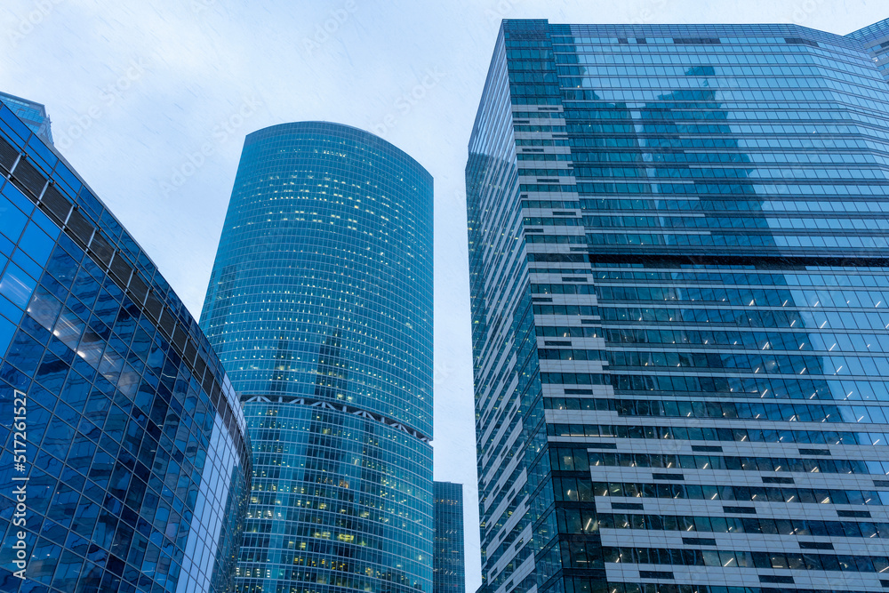 The tops of modern corporate buildings in snowfall. Low angle view of skyscrapers.