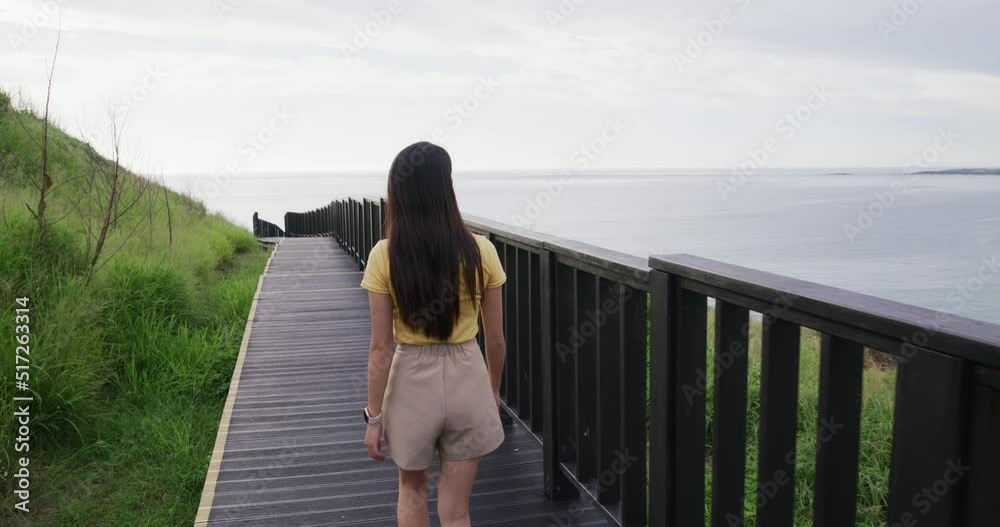 Woman walk over the wooden path beside the sea Woman walk over the wooden path beside the sea