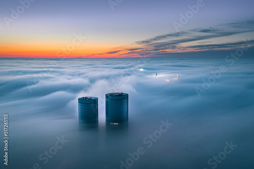 Obraz na płótnie
Skyscraper rooftop over the clouds at sunrise. Thick fog covers the Riga city, and warm sunlight over the clouds.
w salonie