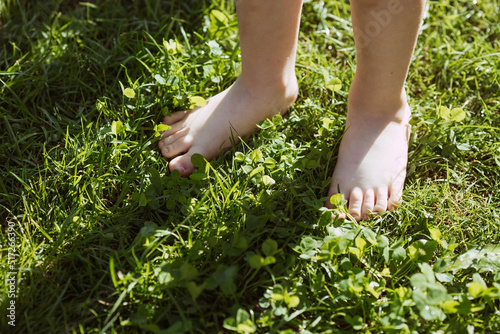 Close-up of a barefoot child walking on a grassy lawn in a park. The concept of a healthy lifestyle, freedom and outdoor recreation.