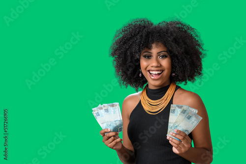 smiling woman holding money in her two hands, Brazilian money, isolated on green background photo