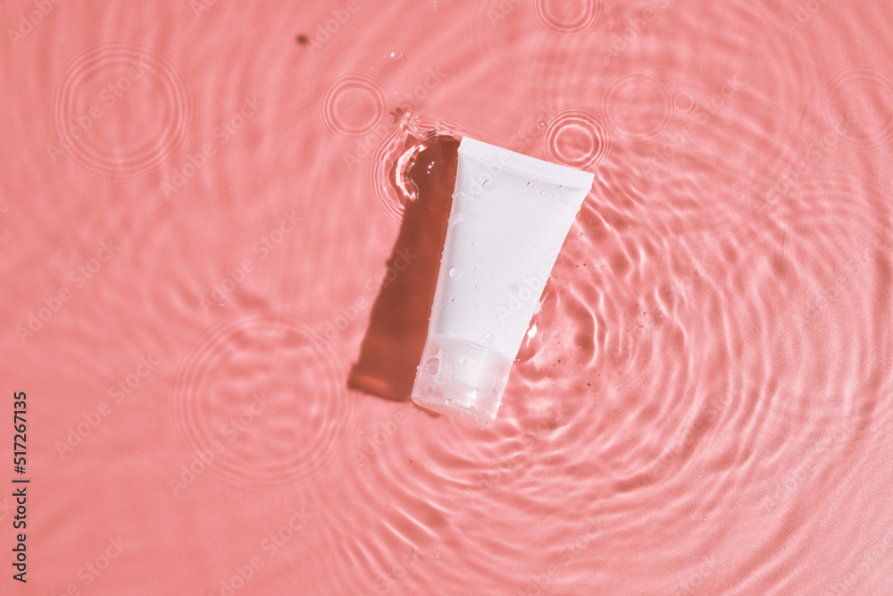 Obraz premium White cosmetic tube on the pink water surface. Blank label for branding mockup. Flat lay, top view. beauty spa medical skincare and cosmetic lotion bottle cream packaging product on pink background.