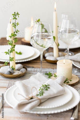Rustic zero waste wedding decor with natural elements. Wooden table  candles  linen napkins  branches with green leaves. Eco-friendly decoration for the special dinner. Romantic and cozy place