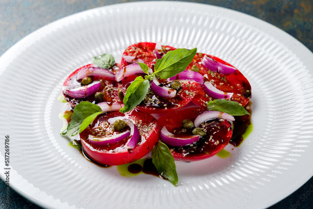 tomatoes bull's heart sliced with red onion on a white plate macro close up tomatoes bull's heart sliced with red onion on a white plate macro close up