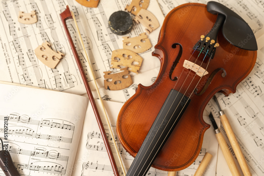 Naklejka premium Violin and bow with tools and music sheets in a workshop