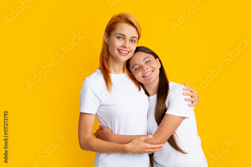 Mother and daughter teenager girl in t-shirt embrace cudding isolated on yellow color background studio. Mothers day love family.