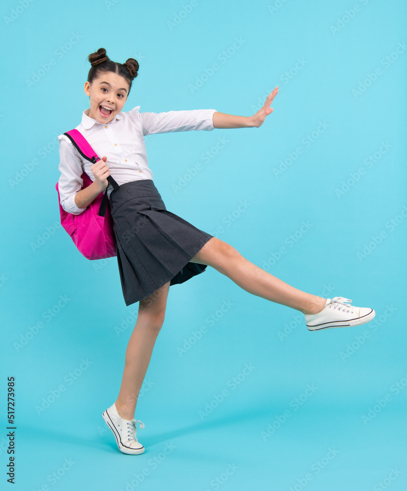 Amazed teenager. Schoolgirl in school uniform with school bag. Teenage girl  student on blue isolated background. Jump and run. Learning knowledge and  children education concept. Excited teen girl. Stock Photo | Adobe