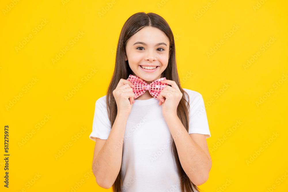 Teenager portrait of smiling girl child in t-shirt with bowtie isolated on yellow background. Teenager portrait of smiling girl child in t-shirt with bowtie isolated on yellow background.